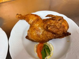 Knusprig gebratenes halbes Hähnchen mit frischer Deko – Spezialität im Restaurant Seequelle.