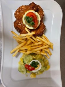 Panierter Schnitzelteller mit Pommes, Gurkensalat und Ei – regionale Küche in Obersulm.